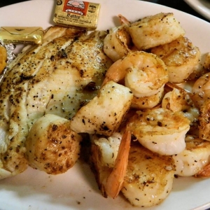 Grilled seafood combo showing fish, shrimp, scallops and a baked sweet potato