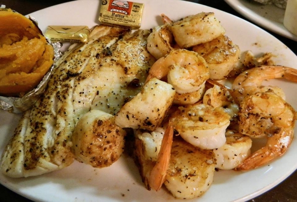 Grilled seafood combo showing fish, shrimp, scallops and a baked sweet potato