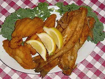 A plate of fried whole catfish and boneless fillets garnished with lemons and kale